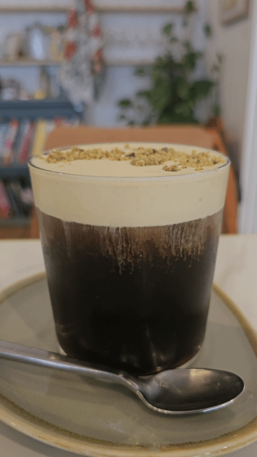 A glass of coffee topped with cream at a local cafe